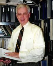 Francis Thomas posing in front his library